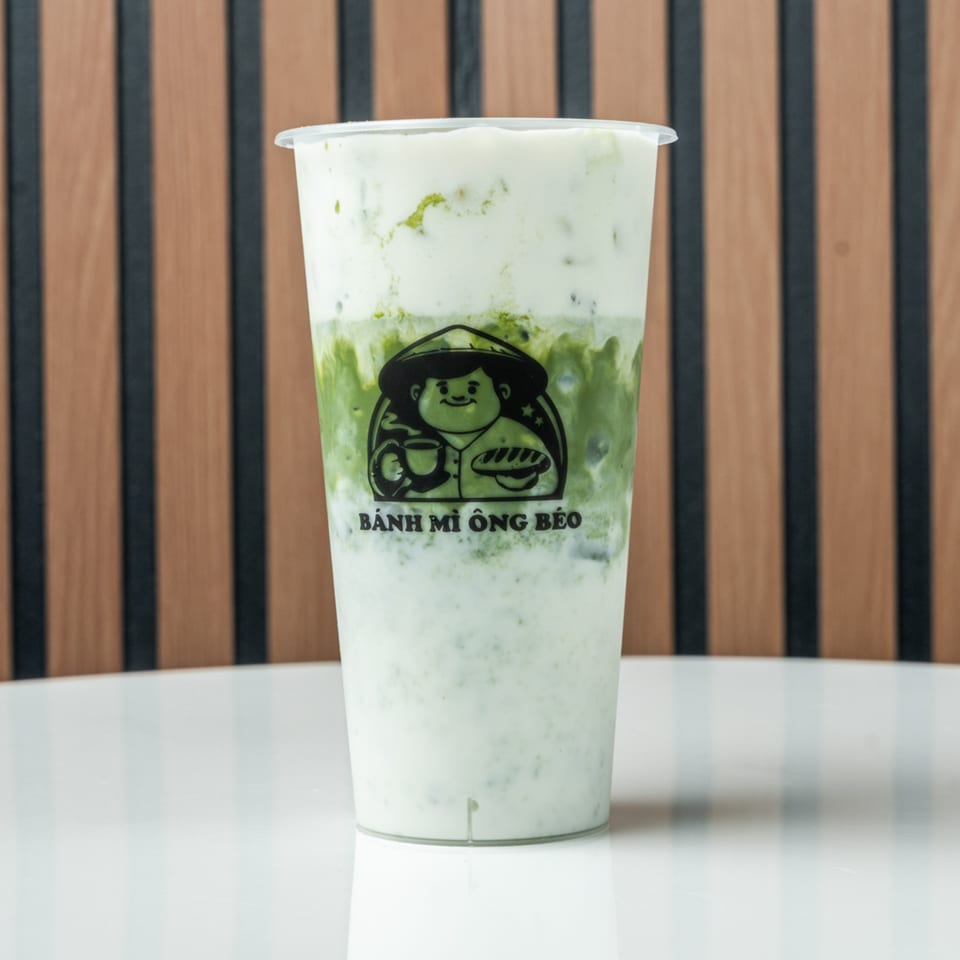 A Banh Mi Ong Beo branded cup filled with a green and white layered drink.