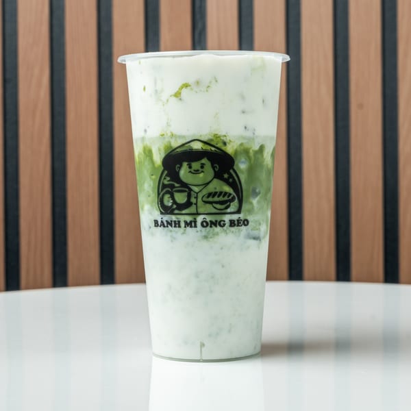 A Banh Mi Ong Beo branded cup filled with a green and white layered drink.