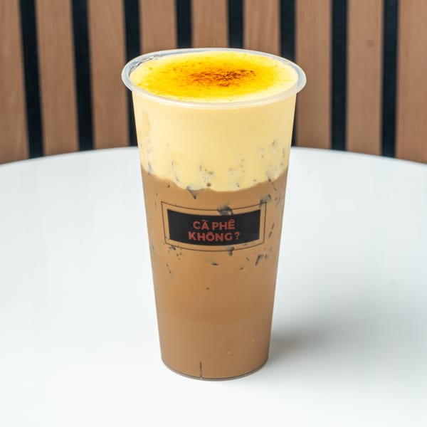 Iced coffee with a thick layer of yellow cream and a "CÀ PHÊ KHÔNG?" label.