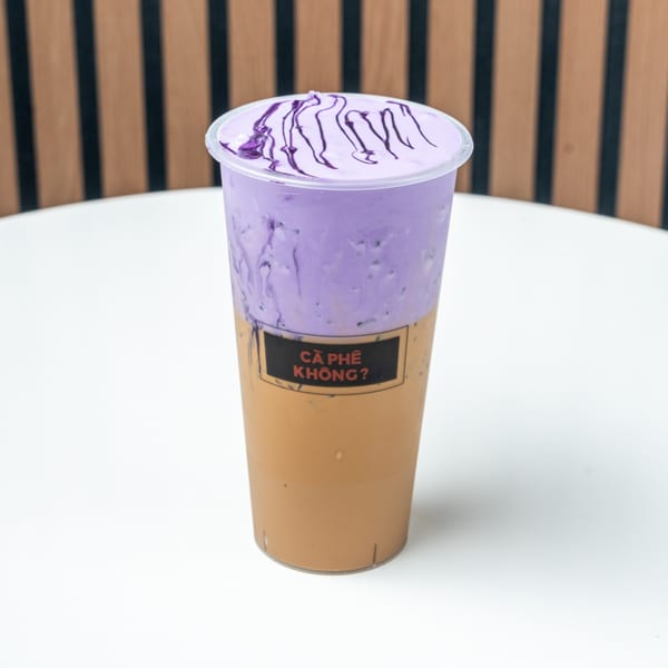 A two-toned drink, purple on top and brown on the bottom, with a "CÀ PHÊ KHÔNG?" label.