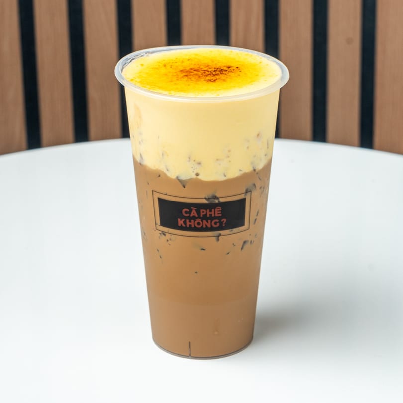 Iced coffee with a thick layer of yellow cream and a "CÀ PHÊ KHÔNG?" label.