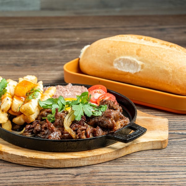 Sizzling beef with onions, fries, pate, tomatoes, and cilantro, served with a baguette.